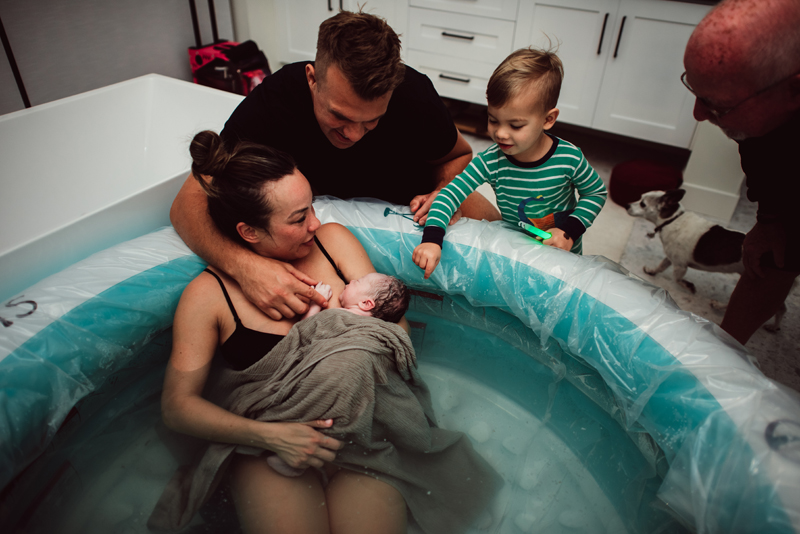 Birth Photography -Woman has give birth and she sits in birthing pool,