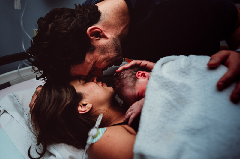 Birth Photography - forehead  to forehead, man and woman joyfully celebrate their newborn baby in mom's arms