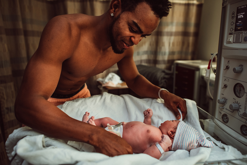 Birth Photography - Father admires newborn baby in hospital