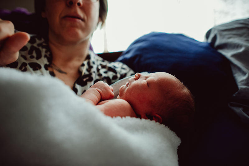 Postpartum Photography - a sleeping baby lays in mother's lap