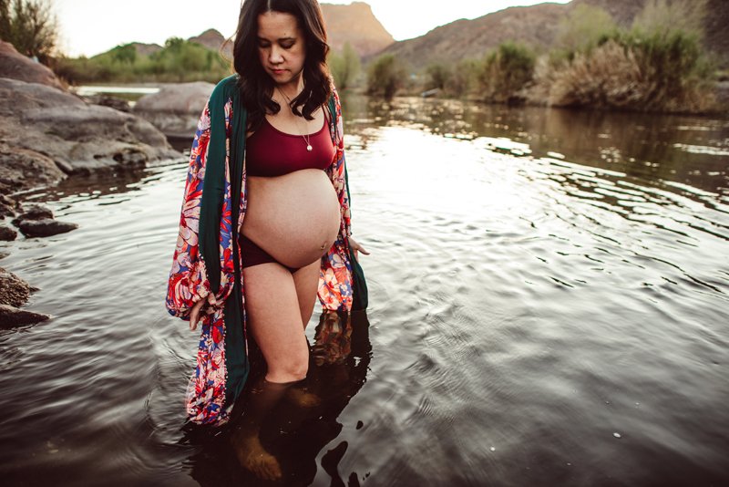 Maternity Photography - an expecting woman walks knee deep in a quiet river