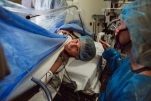 mother smiles while waiting for cesarean birth in operating room