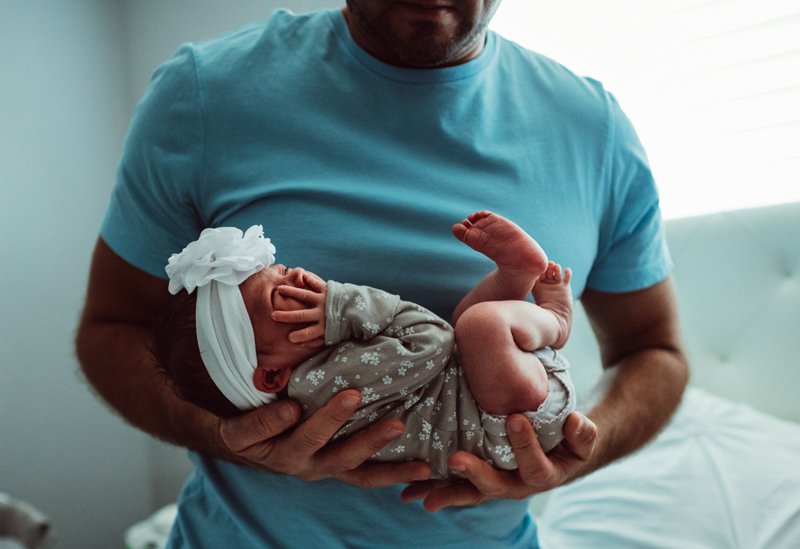 Postpartum Photography - a dad holds his baby daughter close at home