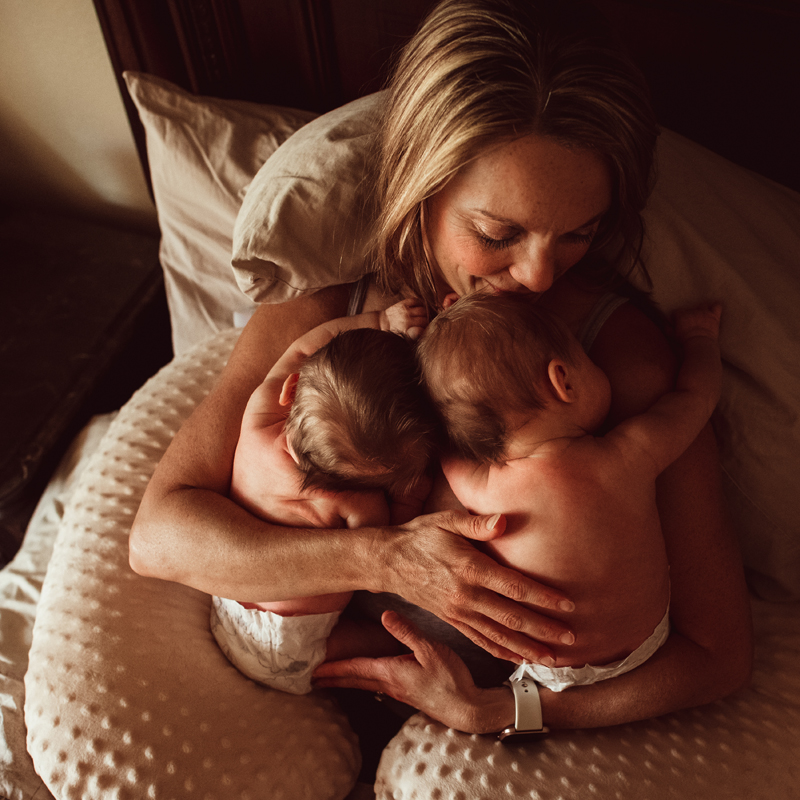 Postpartum Photography - a mother holds her two twin babies close in bed