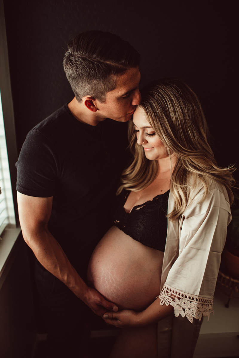 Maternity Photography - man kisses his pregnant partner on the forehead, she smiles