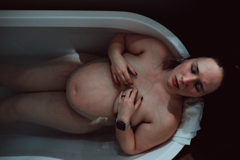 woman closes eyes laying in birth tub